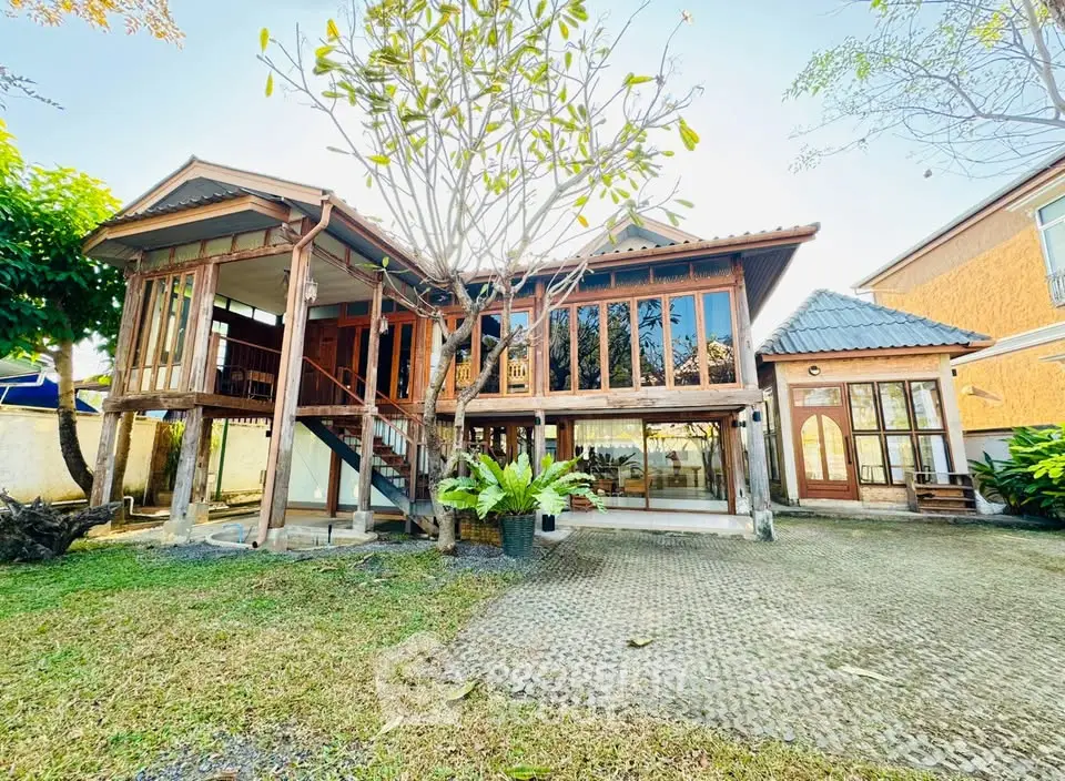 Charming wooden house with large windows and lush garden, perfect for serene living.