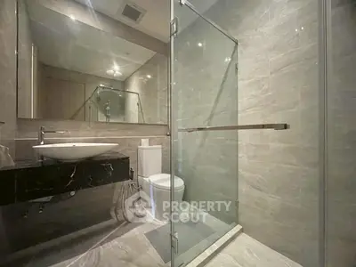 Modern bathroom with glass shower and sleek fixtures in luxury apartment.