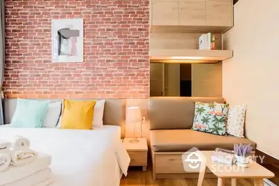 Cozy studio apartment with exposed brick wall, comfortable bed, and modern furnishings, perfect for urban living.