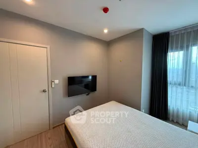 Modern bedroom with wall-mounted TV and large window with curtains