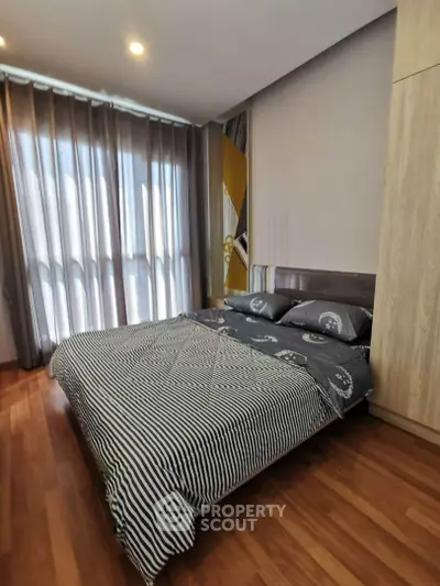 Modern bedroom with stylish decor and natural light, featuring a cozy bed and elegant wooden flooring.