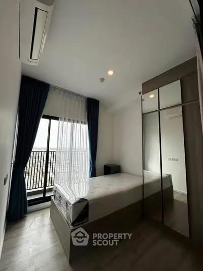 Modern bedroom with large window and mirrored wardrobe in a high-rise apartment.