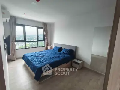 Spacious bedroom with large window offering stunning city views, modern furnishings, and ample natural light.
