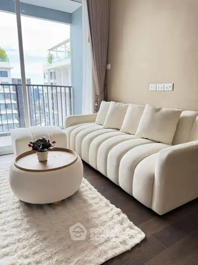 Stylish living room with plush sofa, modern coffee table, and balcony view in contemporary apartment.