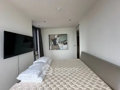 Modern bedroom with minimalist decor and wall-mounted TV in a stylish apartment.