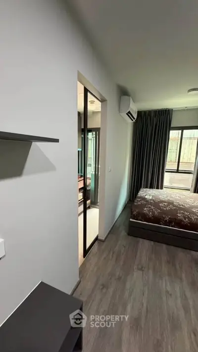 Modern bedroom with large window and air conditioning, featuring stylish flooring and contemporary decor.