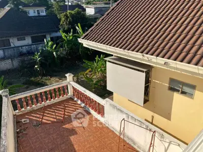Charming house with tiled rooftop and spacious balcony overlooking lush garden.
