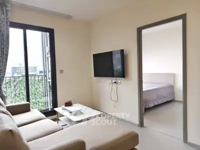 Modern living room with wall-mounted TV and view into cozy bedroom