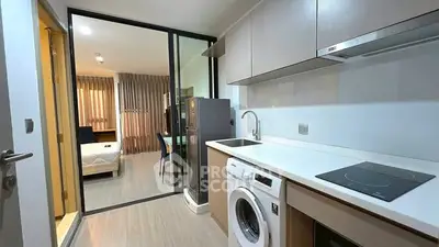 Modern kitchen with washing machine and induction cooktop in open layout apartment.