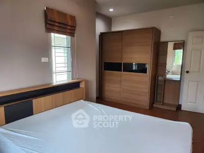 Spacious bedroom with modern wooden wardrobe and large window for natural light.