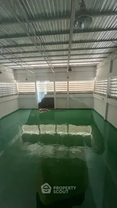 Spacious industrial warehouse with polished green flooring and ample natural light.