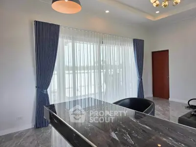 Modern living room with marble table and large window with blue curtains, offering a bright and airy atmosphere.