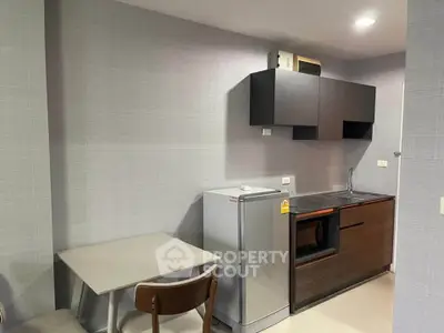 Modern compact kitchen with sleek cabinets and small dining area in a stylish apartment.