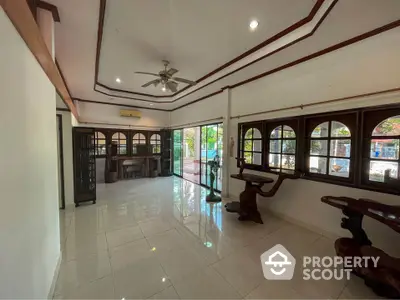 Spacious living room with polished tile flooring, traditional wood trim, and ample natural light from large windows, perfect for family gatherings.