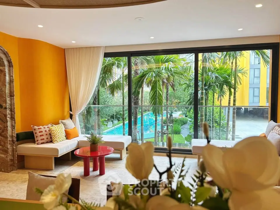 Luxurious living room with large windows overlooking tropical garden and pool, vibrant decor and elegant furnishings.