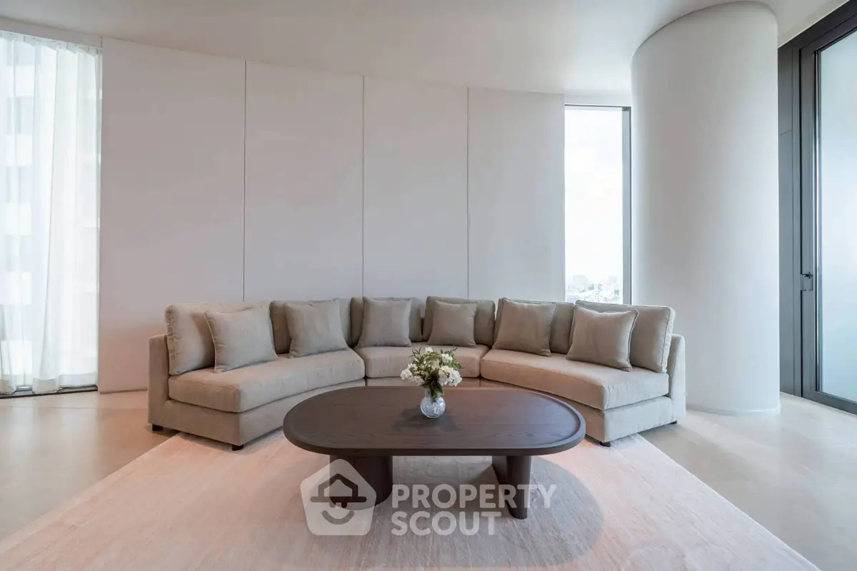 Luxurious modern living room with curved sofa and elegant coffee table in high-rise apartment.