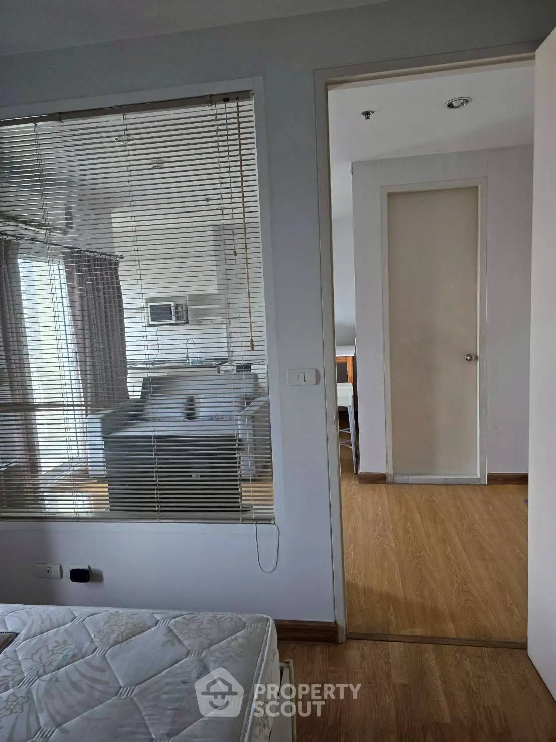 Modern apartment interior with wooden flooring and large windows for natural light.