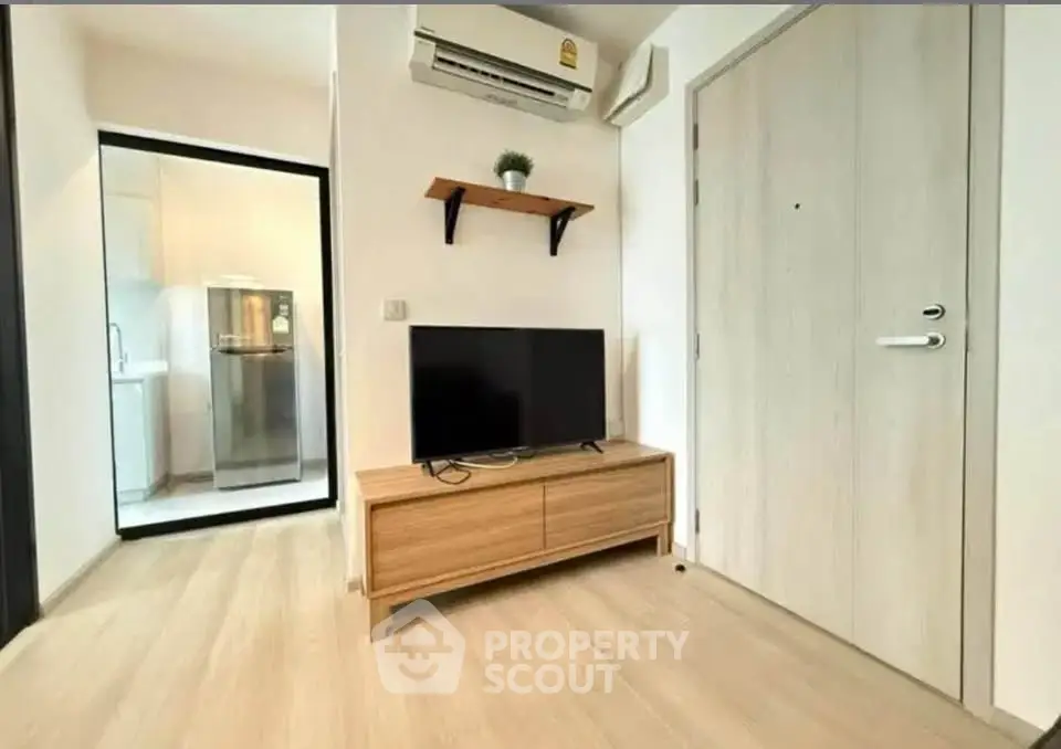 Modern living room with wooden flooring, TV unit, and air conditioning in a cozy apartment.