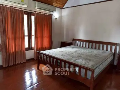 Spacious bedroom with wooden flooring and large windows for natural light.