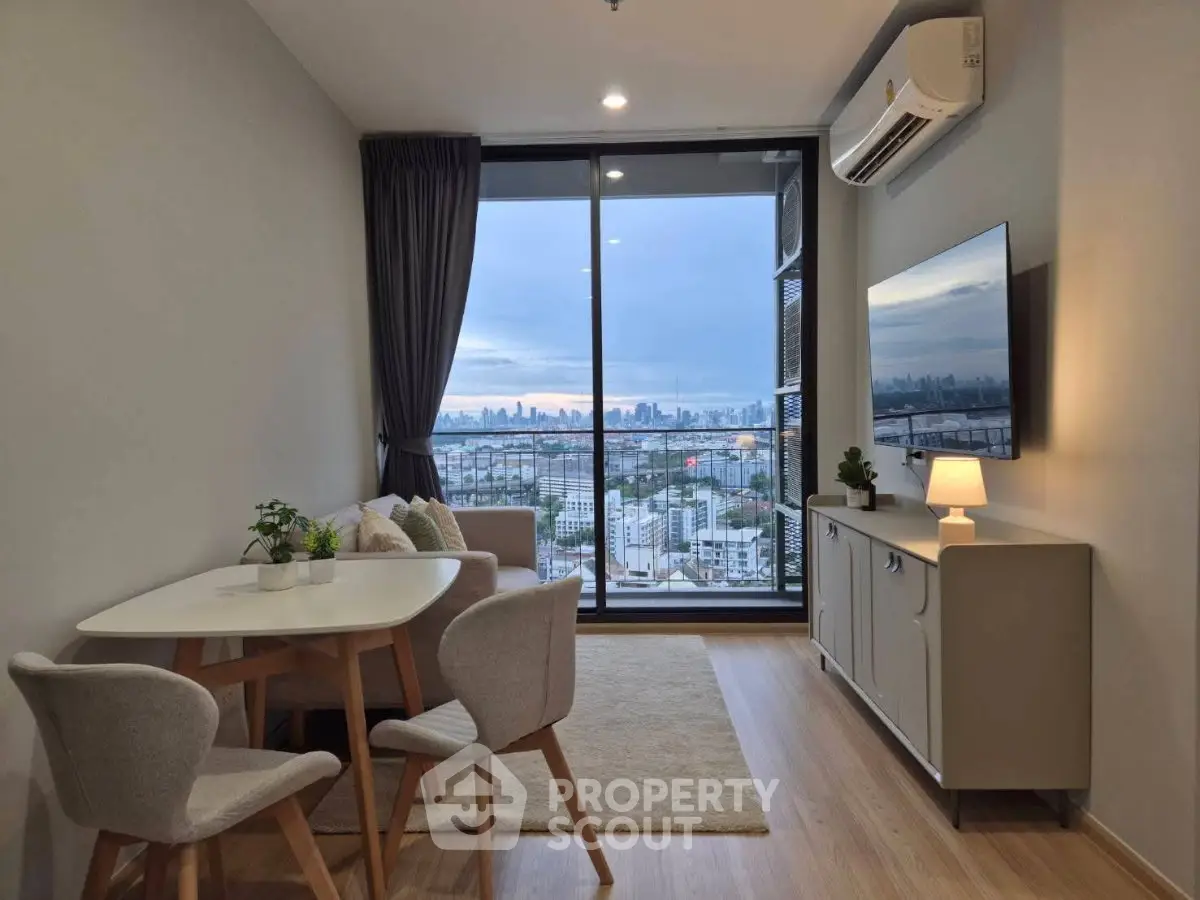 Modern living room with city view, featuring sleek furniture and large windows for natural light.