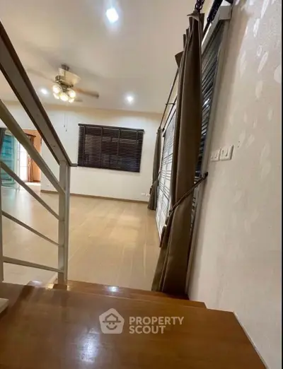 Spacious living room with wooden flooring and large windows for natural light.