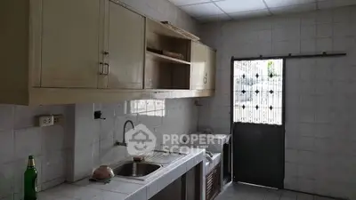 Spacious kitchen with tiled walls and natural light, featuring a sink and storage cabinets.