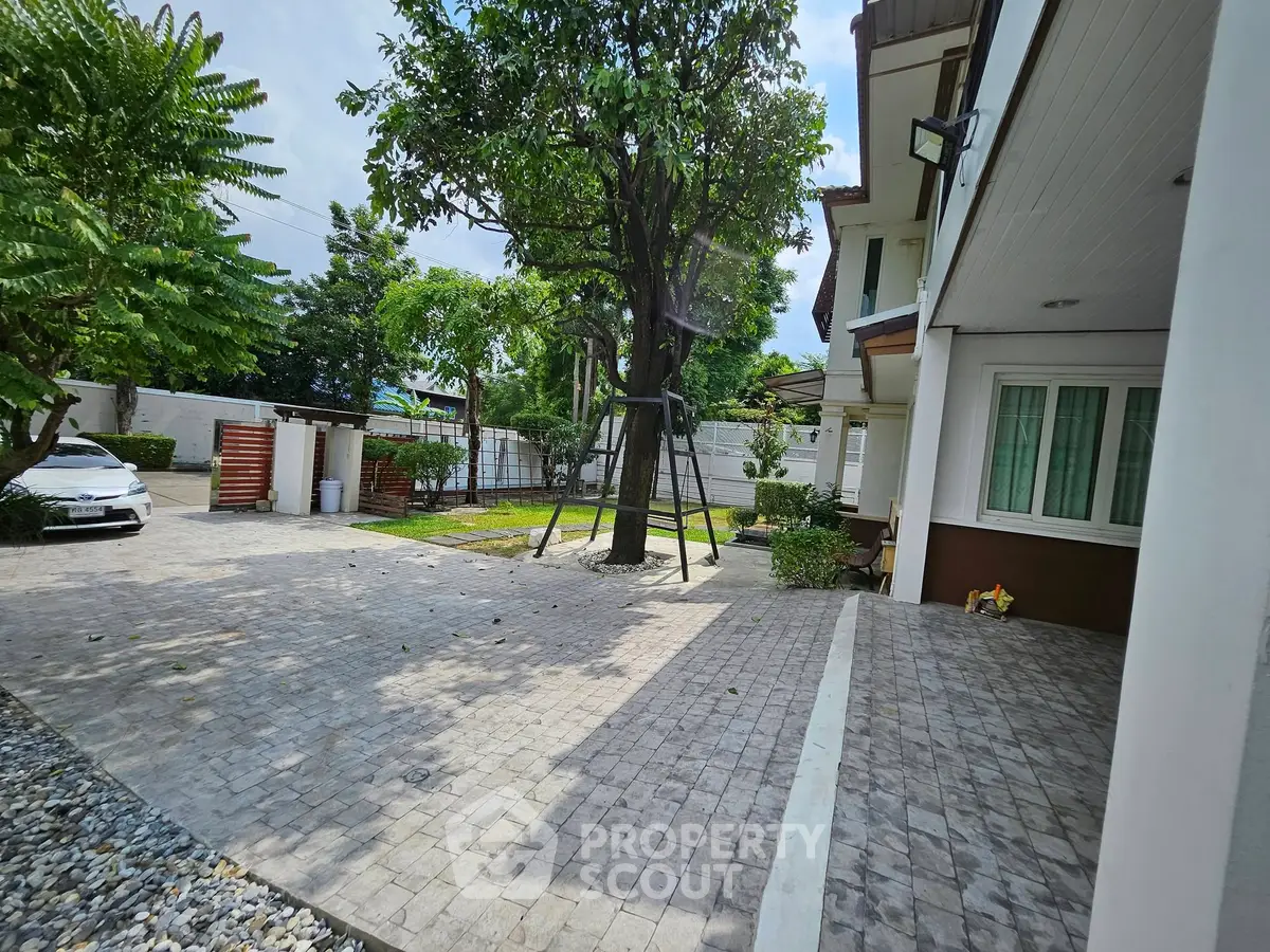 Spacious garden area with paved driveway and lush greenery in a modern residential property.