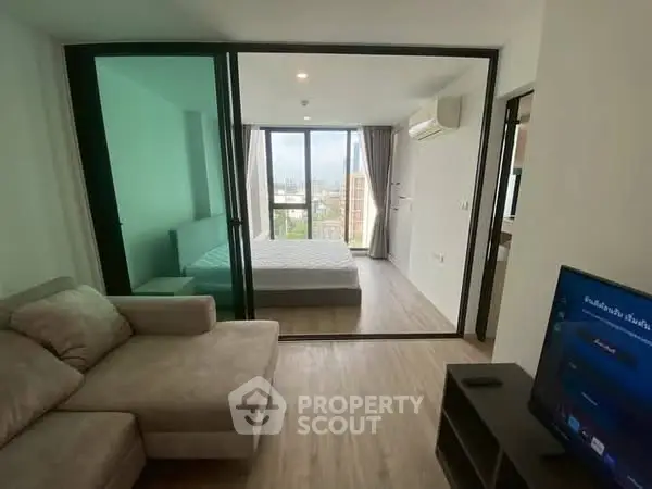 Modern apartment with spacious living room and bedroom, featuring large windows and a city view.