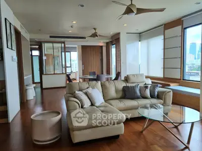 Spacious modern living room with city view, featuring elegant furniture and wooden flooring.