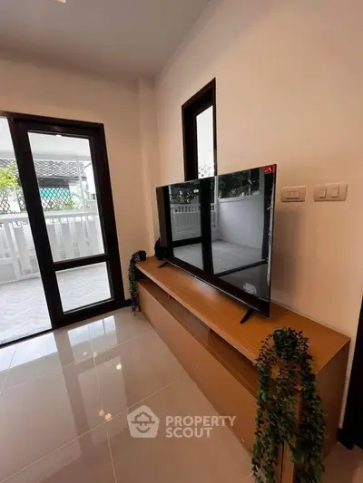Modern living room with sleek TV unit and balcony access, perfect for relaxation and entertainment.
