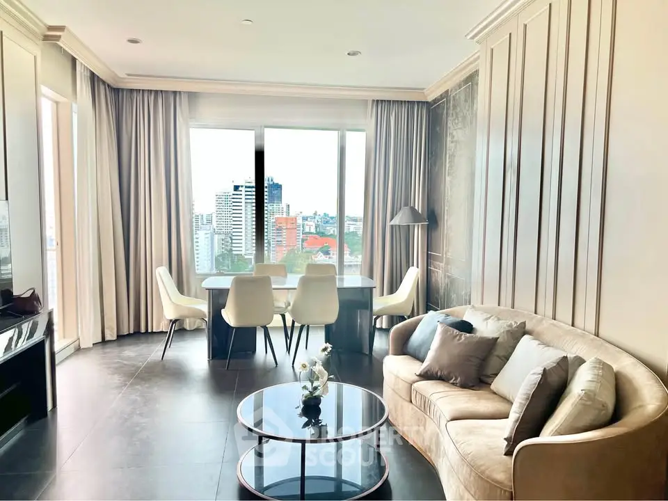 Elegant living room with city view, featuring modern furniture and large windows for natural light.