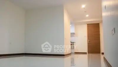 Spacious empty apartment interior with glossy tiled floors and modern wooden door.