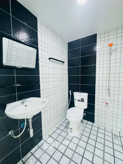 Modern bathroom with black and white tiles, wall-mounted sink, and shower area.