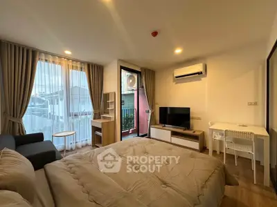 Modern bedroom with balcony, featuring cozy bed, TV, and study desk in stylish apartment.