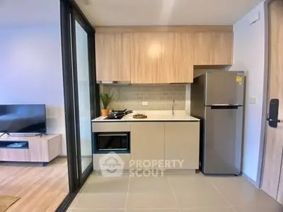Modern kitchen with sleek cabinetry and stainless steel appliances in open layout apartment.
