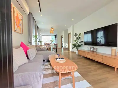 Spacious modern living room with stylish decor and large TV, perfect for relaxation and entertainment.