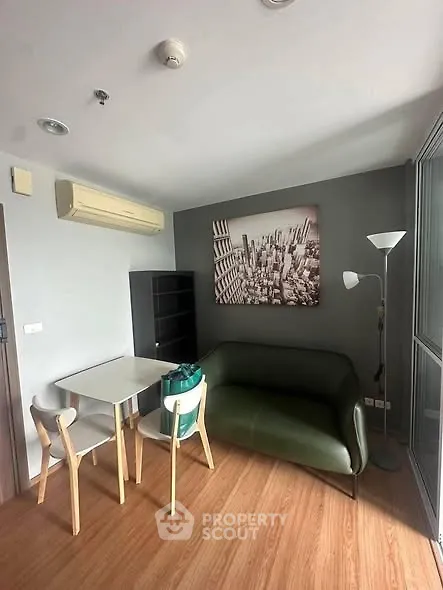 Modern living room with stylish furniture and cityscape artwork, featuring a cozy green sofa and dining area.