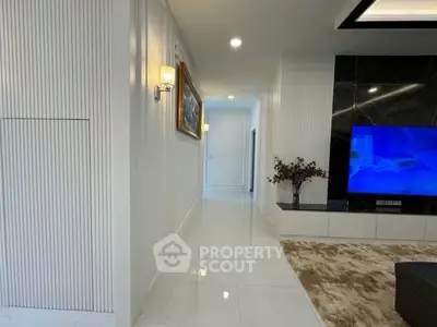 Modern living room with sleek design, featuring a large TV and elegant lighting.
