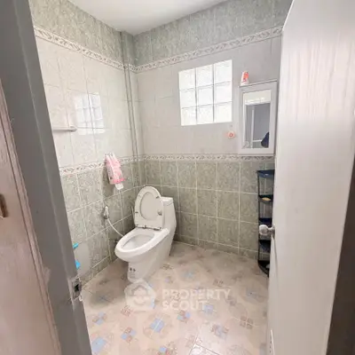 Spacious bathroom with modern toilet and tiled walls in a cozy home.
