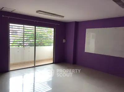 Spacious room with purple walls and balcony access, ideal for versatile use.