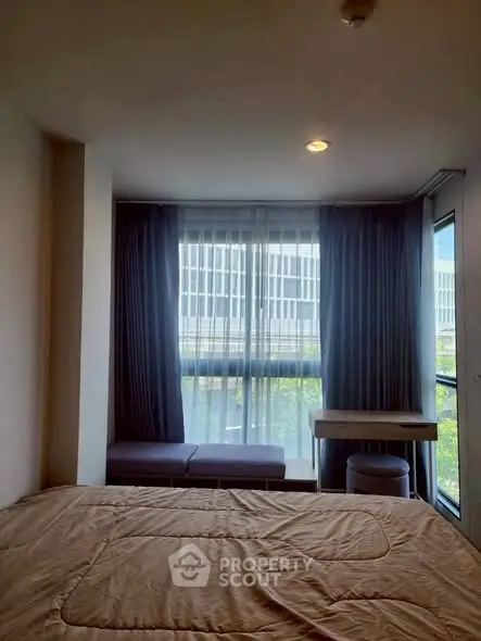 Cozy bedroom with large window and modern furnishings in a stylish apartment.