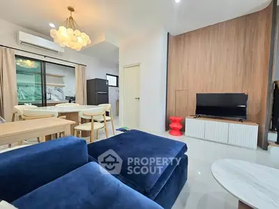 Modern living room with blue sofa, dining area, and stylish lighting
