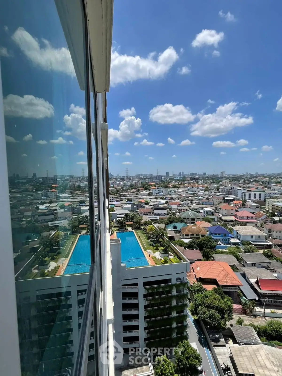 Stunning high-rise view with pool and cityscape under a clear blue sky.