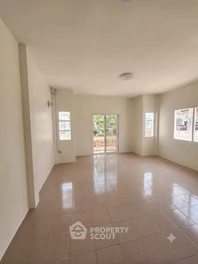 Spacious empty living room with large windows and tiled floor, ready for customization.