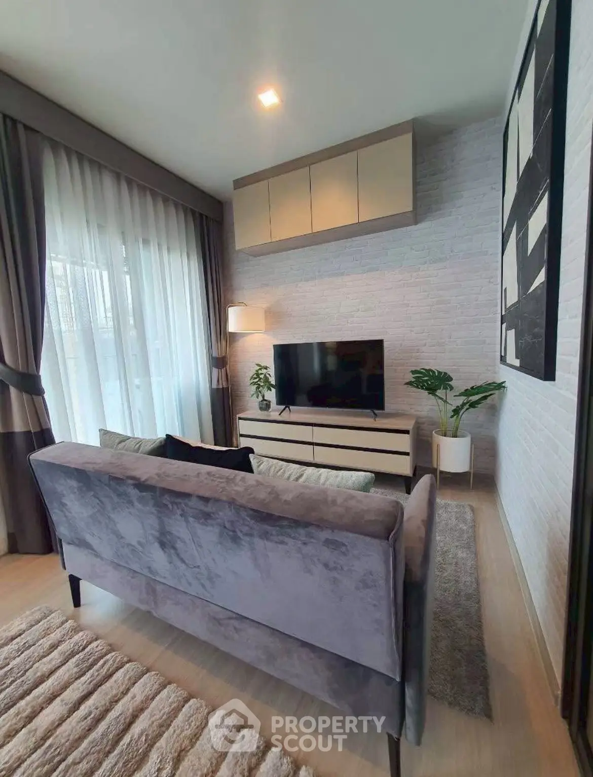 Stylish living room with modern decor, cozy sofa, and large TV, perfect for relaxation and entertainment.