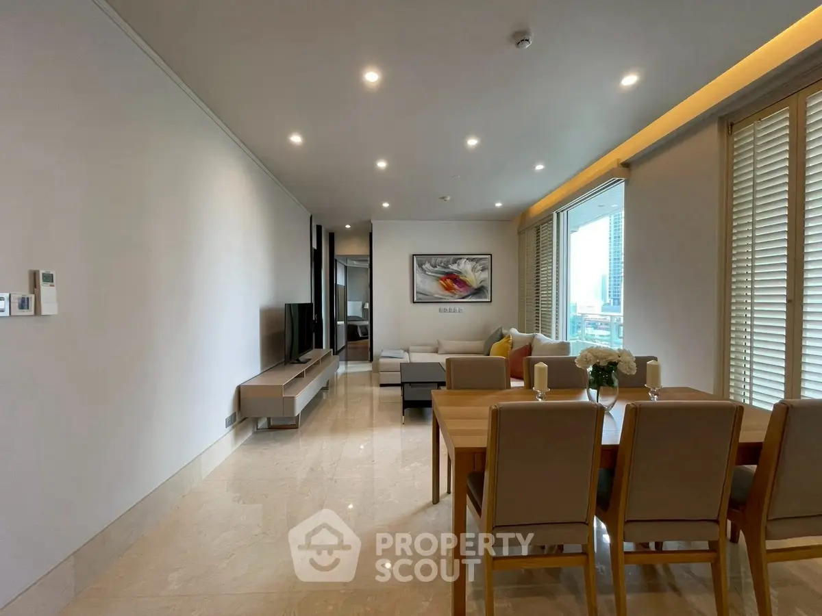 Spacious modern living room with dining area and city view, featuring elegant decor and ample natural light.