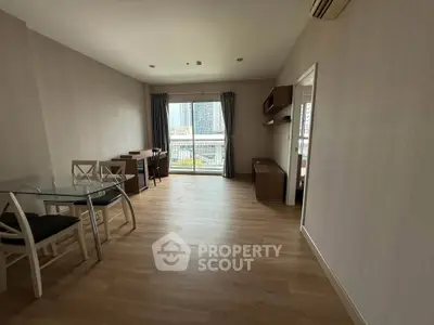 Spacious living room with wooden flooring and balcony view in modern apartment.