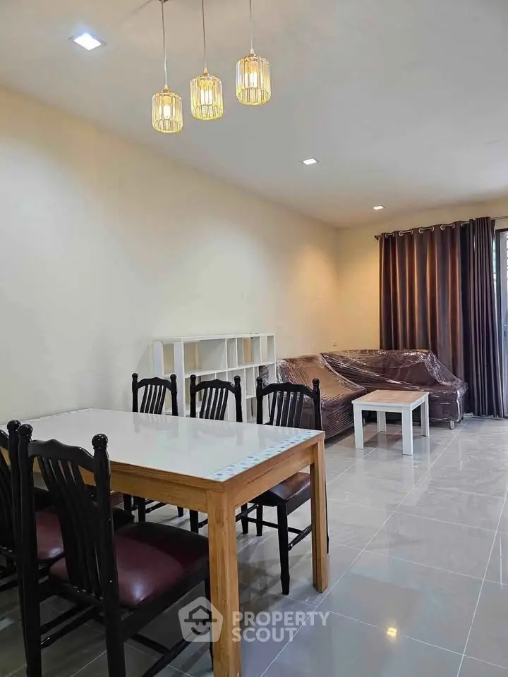 Spacious living room with modern dining area and elegant lighting fixtures.