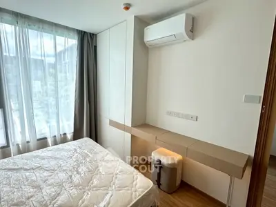 Modern bedroom with built-in storage and air conditioning, featuring large window for natural light.