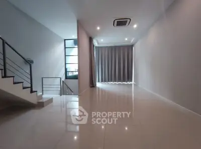 Spacious modern living room with sleek staircase and large windows